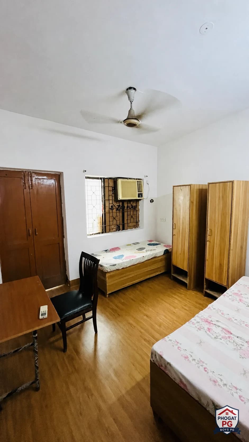Two beds, wardrobes, desk and chair in a Phogat PG room