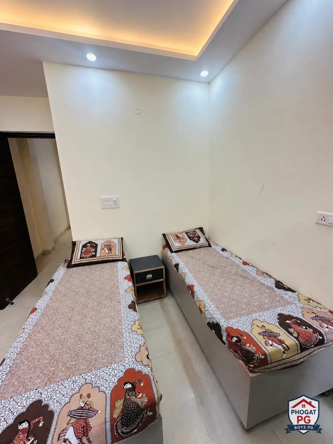 Two single beds with a bedside table in a Phogat PG room