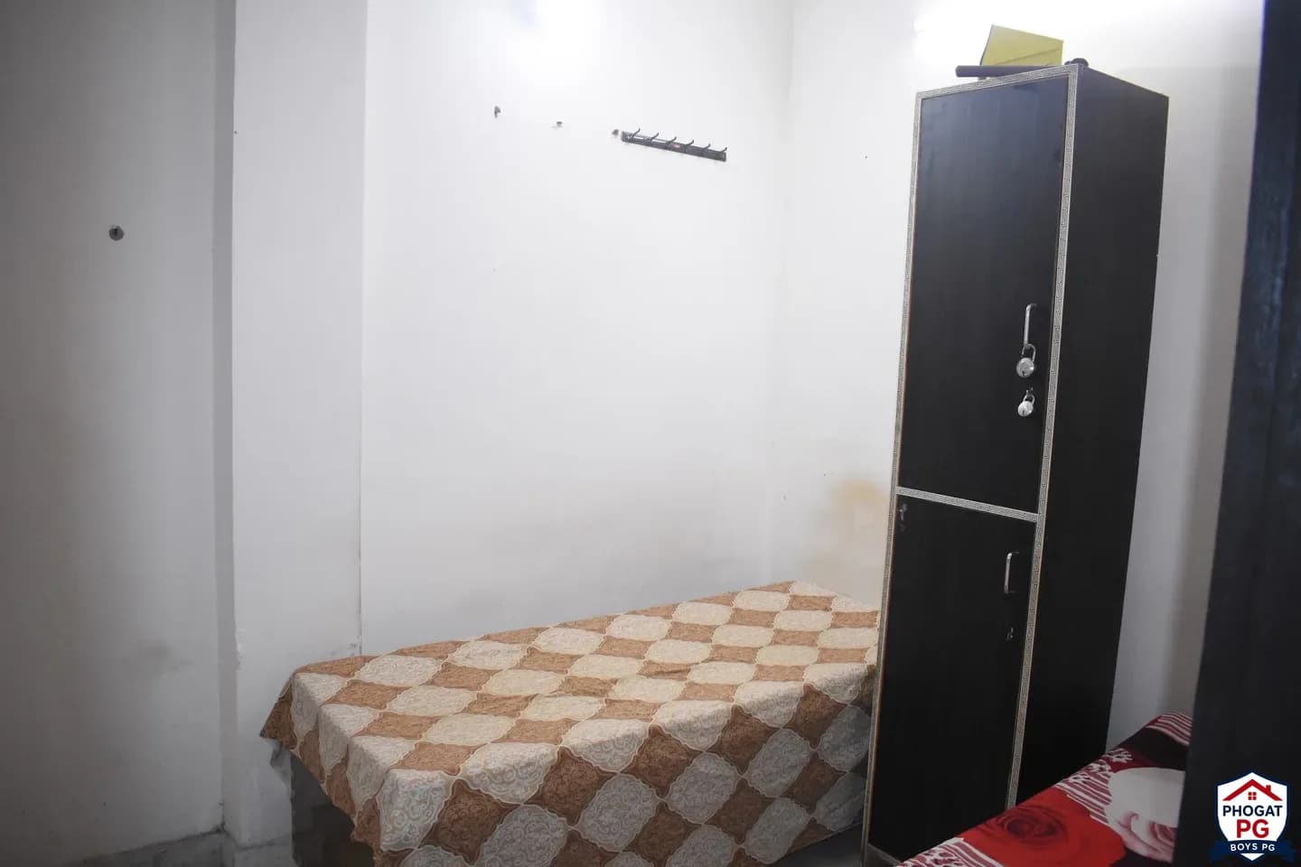 One visible bed with checkered bedding and a lockable wardrobe