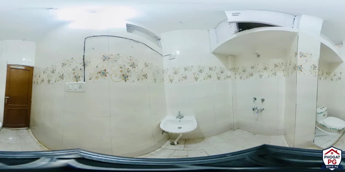 Wide bathroom view showing a wash basin, shower taps and toilet