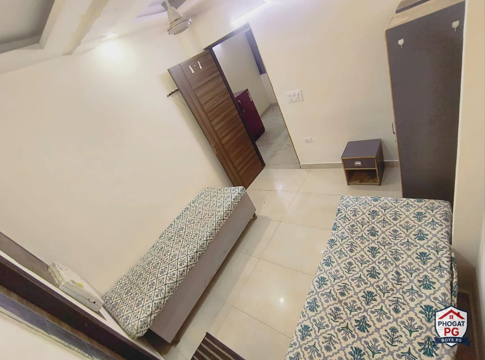 Two single beds, wardrobes and tiled floor in a Phogat PG room